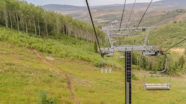 公园城滑雪胜地的全景阳光休憩季节景观，带椅子电梯，俯瞰远足小径 — 图库照片