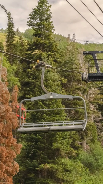 Vertikala stolslyftar mot levande gröna träd och molnig himmel på Park City i lågsäsong — Stockfoto