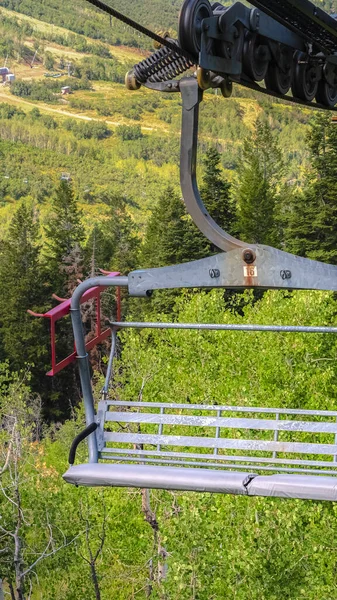 Vertikal Närbild av en stolslift över berget med vandringsleder och träd vid lågsäsong — Stockfoto