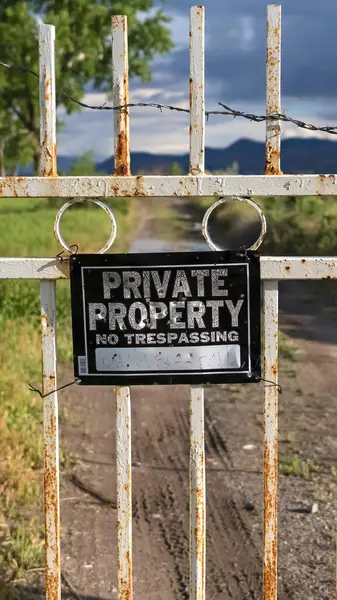 Vertical Fechar de um portão trancado em uma propriedade privada com vista para o lago e montanha — Fotografia de Stock