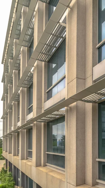 Vertical Close up of the glass windows and concrete exterior wall of a modern building