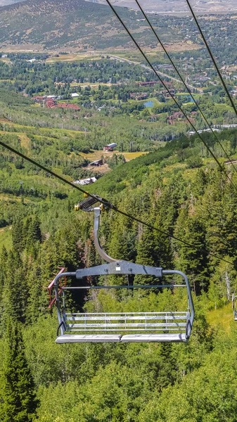 Vertical frame Chairlifts against green trees and mountain with hiking trails at off season — Stockfoto