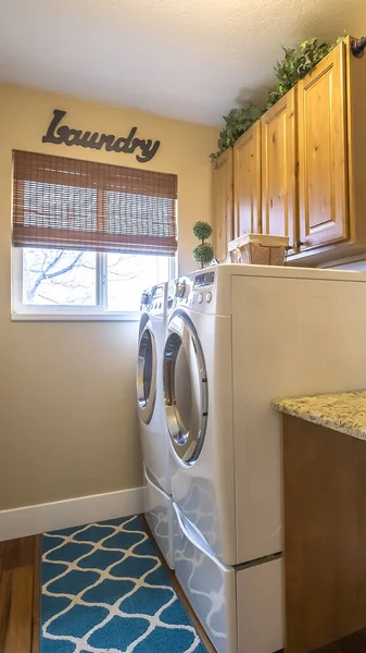 Vertical frame Laundry room of a home with washing machine against the wall and small window