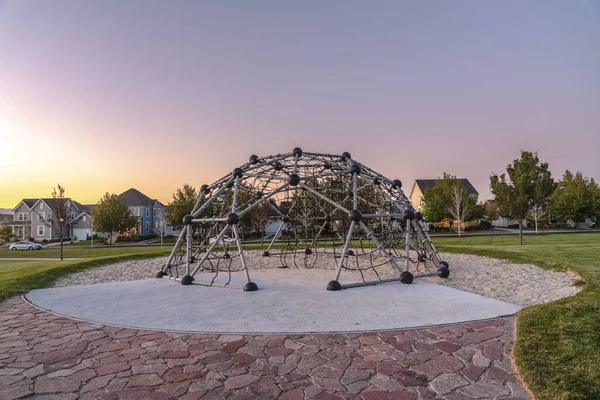 Metal climbing frame in a playground at sunset