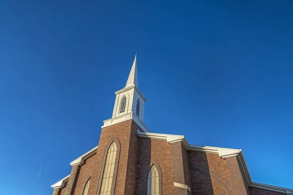 Iglesia con la clásica pared exterior de ladrillo rojo y campanario blanco contra el cielo azul — Foto de Stock