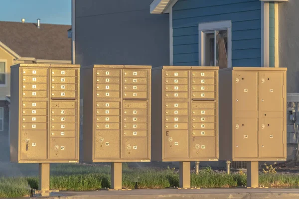 Row of mailboxes with numbers and compartments beside a road on a sunny day — Stockfoto