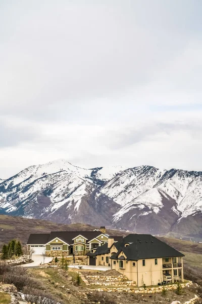 Quartier résidentiel sur une colline avec des maisons de luxe donnant sur une montagne enneigée — Photo