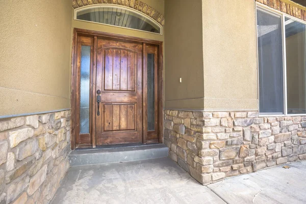 Коричневая деревянная входная дверь дома с боковыми дверями и арочным окном — стоковое фото