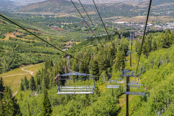 Stoelen liften tegen groene bomen en berg met wandelpaden in het laagseizoen — Stockfoto