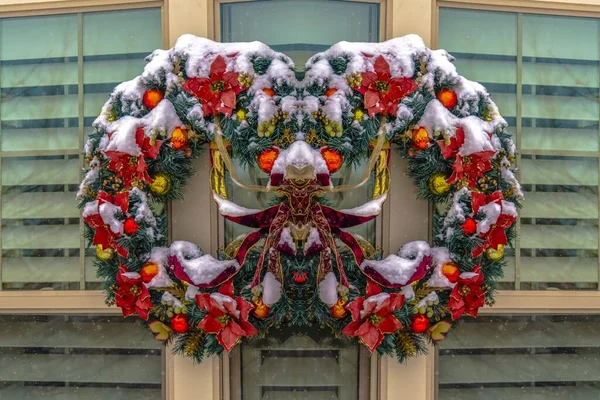 Reflexão simétrica de uma grinalda de Natal colorida coberta de neve contra a janela — Fotografia de Stock