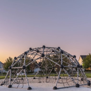 Gün batımında bir oyun parkında kare çerçeve Metal tırmanma çerçevesi