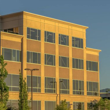 Güneşli bir günde dağ ve gökyüzü arkaplanı olan kare çerçeveli ticari bina.