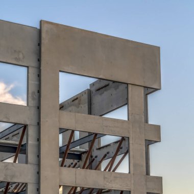 Günbatımında gökyüzü ve bulutlara karşı inşa halinde olan modern binanın kare dış cephesi