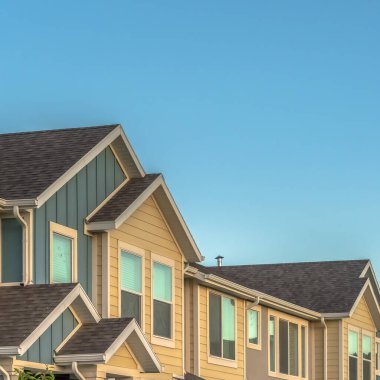 Güneşli bir günde mavi gökyüzü arka planına sahip kasaba evlerinin üst katının kare dış cephesi