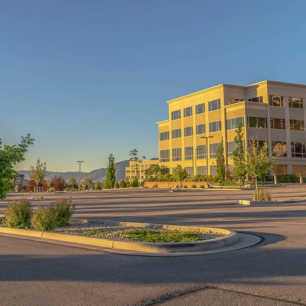 Fachada cuadrada de un edificio de oficinas contemporáneo con estacionamiento en un día soleado — Foto de Stock