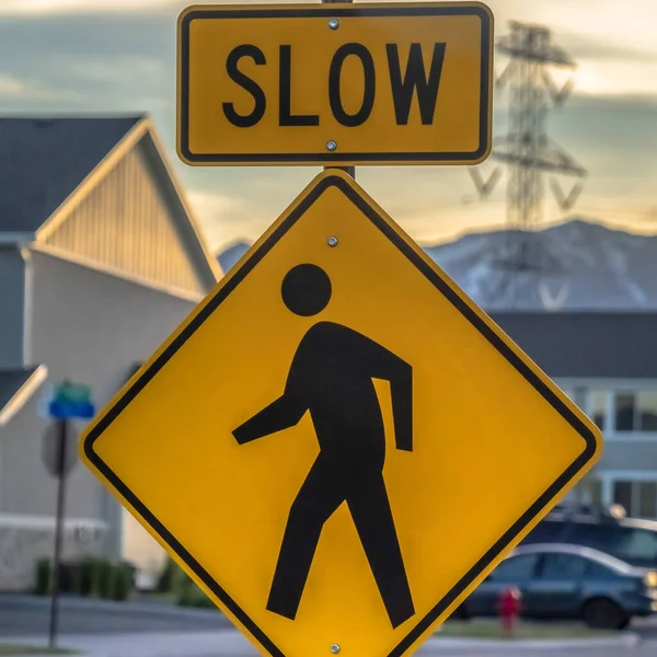 Square Pedestrian crossing road sign against houses vehicles mountain and cloudy sky — Stock Photo, Image