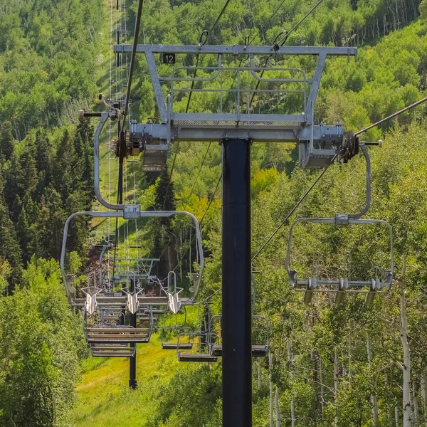 Quadratische Sessellifte über üppig grüne Bäume und Wanderwege in der Nebensaison — Stockfoto