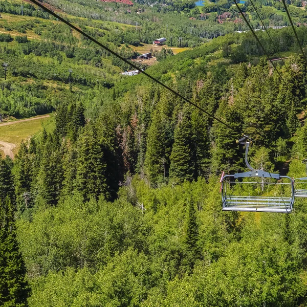 Vierkante frame Stoelen liften over wandelpaden en bomen op de berg met gebouwen in Park City — Stockfoto