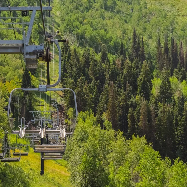 Vierkante frame stoeltjesliften over overvloedige groene bomen en wandelpaden in het laagseizoen maanden — Stockfoto