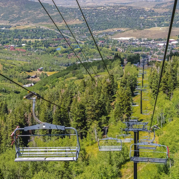 Vierkante stoeltjesliften tegen groene bomen en berg met wandelpaden in het laagseizoen — Stockfoto