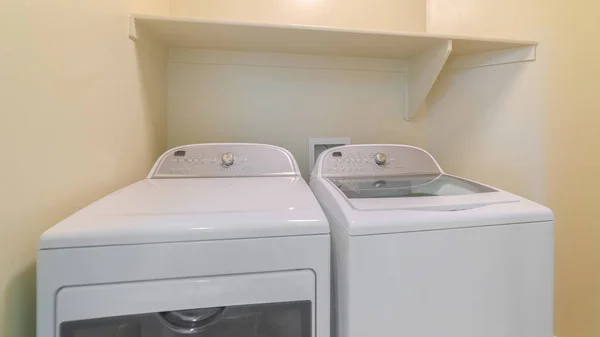 Panorama cadre Machine à laver et sèche-linge à l'intérieur d'une buanderie avec étagère et mur beige — Photo