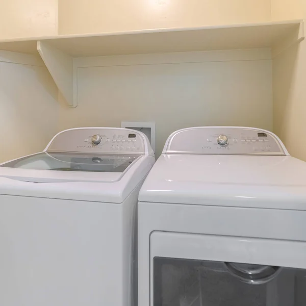 Квадратная стиральная машина и сушилка внутри лаунжа с бежевыми стенами — стоковое фото