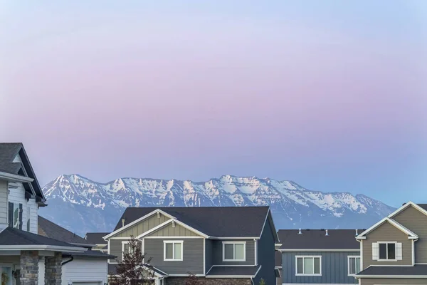 Häuserfront mit grauen Wänden und Satteldächern gegen schneebedeckten Berg — Stockfoto
