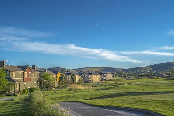 Casas em torno de um campo de golfe com fundo cênico de montanha e céu azul — Fotografia de Stock