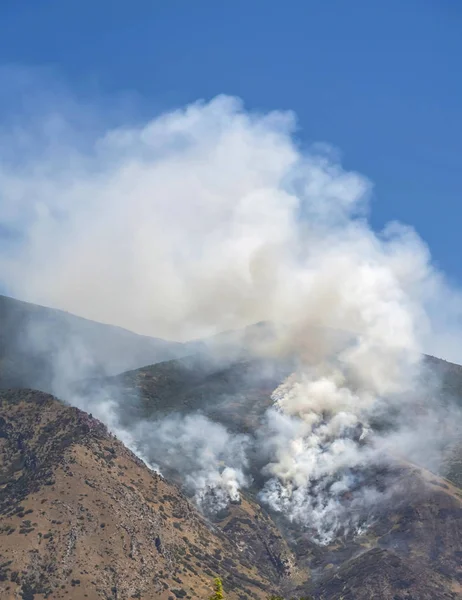Aerial view of mountain with white smoke from wild forest fire on a sunny day — Stock Photo, Image