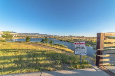 Güneşli bir günde, patikaları ve köprüsü olan sığ bir gölde atlama uyarısı yok.