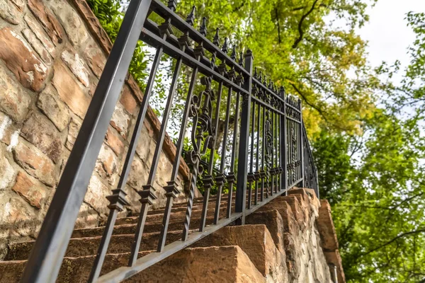 Primo piano di ringhiera in metallo e battistrada in pietra di una scala contro recinzione in pietra — Foto Stock