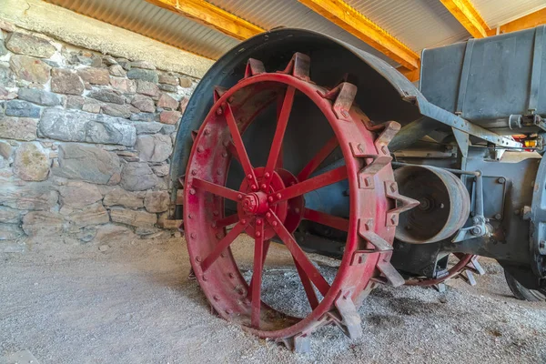 Llanta de rueda roja de un tractor vintage contra la pared de piedra de un granero de granja — Foto de Stock