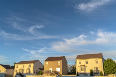 Güneşli bir günde balkonları merdivenleri, pencereleri ve çitleri olan bir ev.