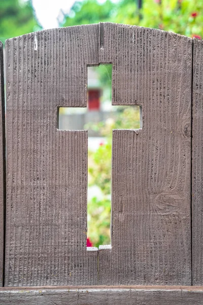 Cross shaped opening in a rustic wooden fence