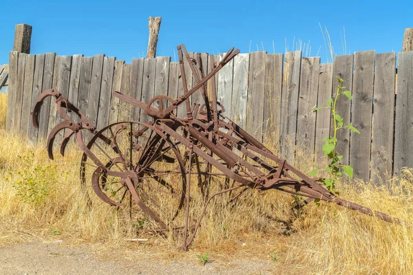 Old vintage farming tractor against grasses and wooden fence on a sunny day — 스톡 사진