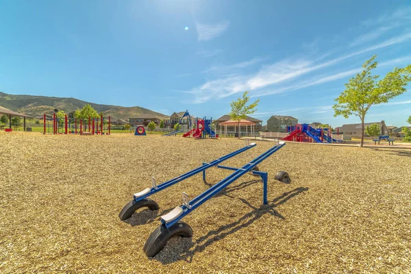 Bright blue see saw at a playground with Timpanogos Mountains and blue sky view