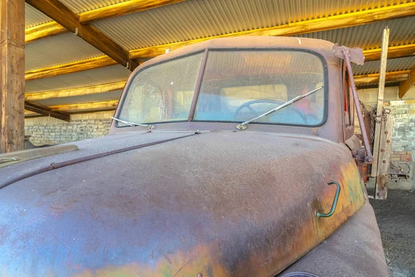 Antiguo coche vintage con exterior oxidado y sucio dentro de un garaje con techo de metal — Foto de Stock