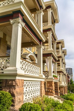 Dekoratif kare sütunlar ve kafes korkuluklarıyla çerçevelenmiş şehir evleri.
