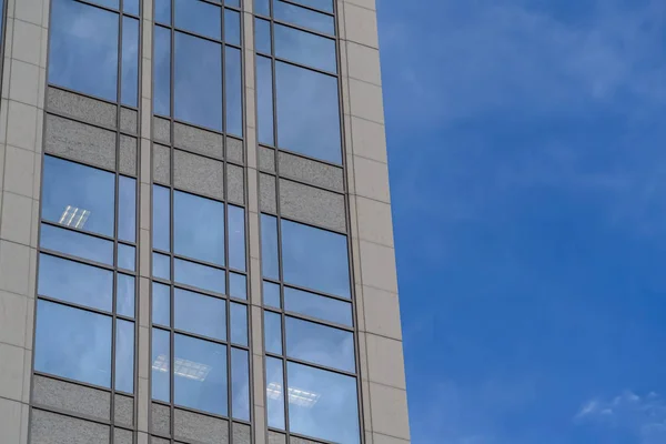 Enfócate en un moderno edificio exterior con ventanas de vidrio que reflejan el cielo azul — Foto de Stock