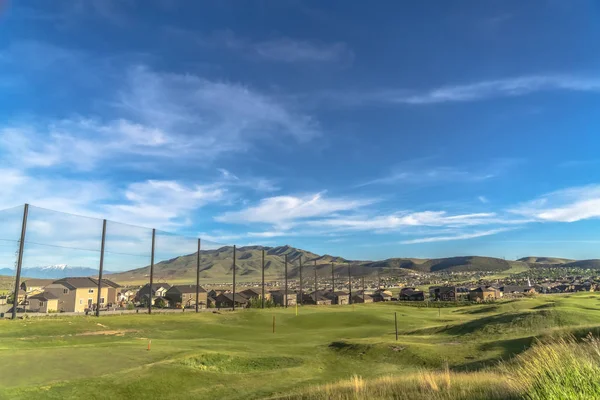 Parcours de golf fairway et de mettre vert avec des bâtons de drapeau sous le ciel bleu et les nuages — Photo