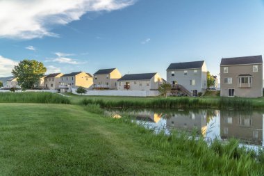 Yeşil çimenli arazi ve aile geçmişine sahip bir parkta parlak bir gölet.