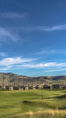 Dikey çerçeve golf sahası çimenliği ve mavi gökyüzü ve bulutların altına yeşil bayraklar yerleştirmek