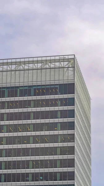 Marco vertical Moderno edificio comercial exterior con altas ventanas de vidrio contra el cielo nublado — Foto de Stock