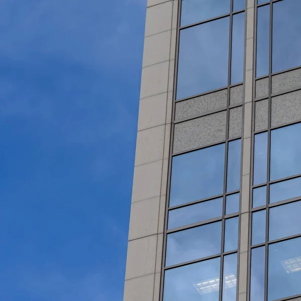 Marco cuadrado Enfoque en un edificio moderno exterior con ventanas de vidrio que reflejan el cielo azul — Foto de Stock