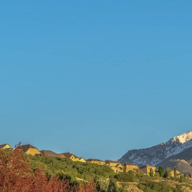 Kare çerçeveli evler karlı dağ manzaralı ve bulutsuz mavi gökyüzü
