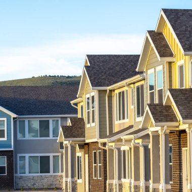 Kare sütunlarla çerçevelenmiş, çatılı ve merdivenli kare evler.