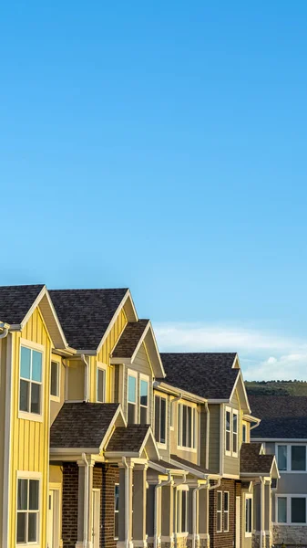 Adosados verticales con pared exterior de madera y ladrillo contra montaña y cielo azul — Foto de Stock