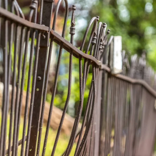 Square frame Sunny day view of fence on top of stone wall against blurred trees and sky — 스톡 사진