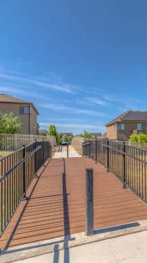 Evleri dağ ve mavi gökyüzü arka planına sahip çimenli bir arazi üzerinde dikey çerçeve Köprüsü