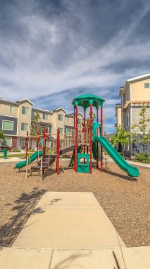 Çocukların oyun alanlarını çevreleyen dikey çerçeve Kasaba evlerine ve bulutlu mavi gökyüzüne karşı